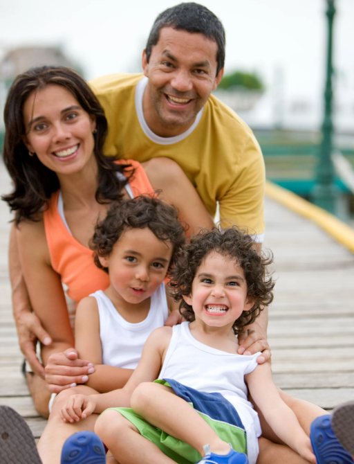 Pais e duas crianças sorrindo em um deck durante ensaio de família