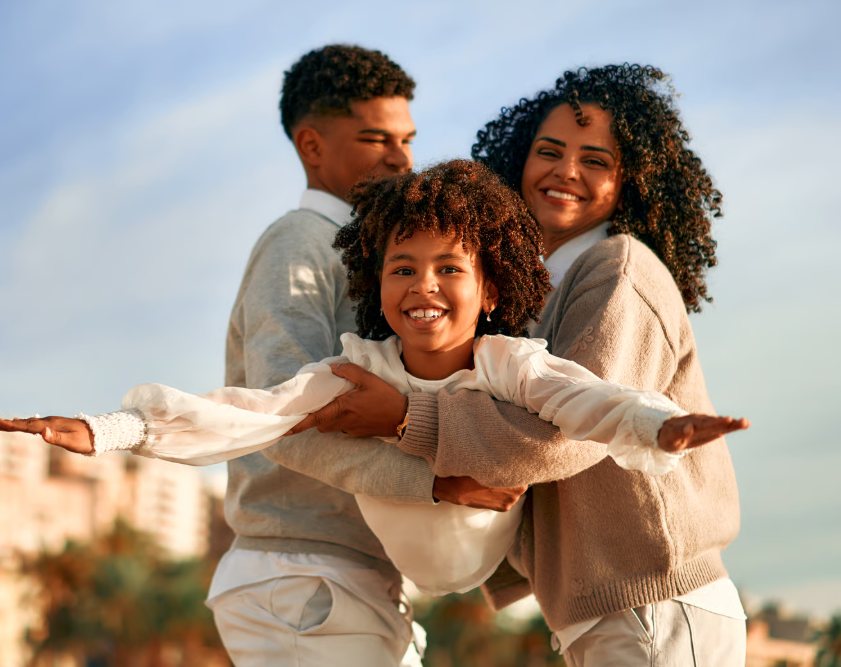 Família sorrindo ao ar livre com criança nos braços