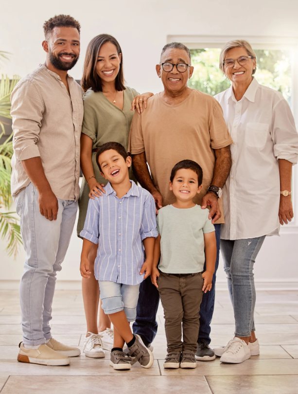 Família de três gerações sorrindo em um ambiente claro durante ensaio fotográfico